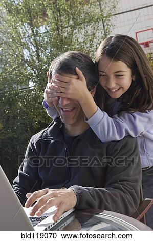Hispanic girl covering father's eyes View Large Photo Image Stock Image - Hispanic girl covering father's eyes. Fotosearch