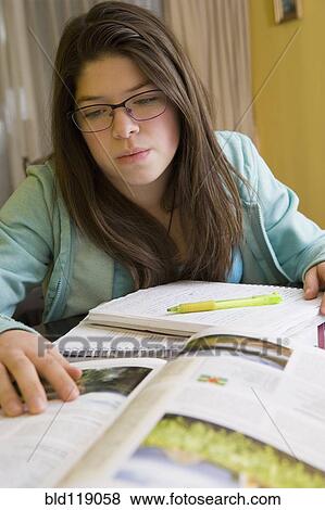 Stock Photo - Hispanic girl doing homework at table. Fotosearch