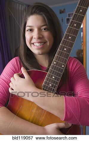 Stock Photo - Hispanic girl hugging guitar. Fotosearch