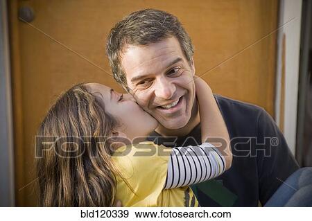 Stock Photo - Hispanic girl kissing father's cheek. Fotosearch