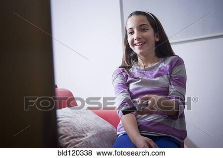 Hispanic girl watching television on sofa View Large Photo Image Stock Photo - Hispanic girl watching television on sofa. Fotosearch