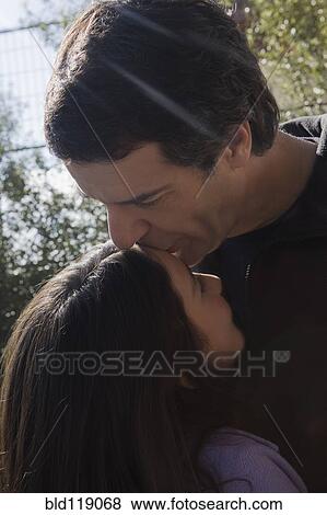 Stock Photo - Hispanic man kissing daughter's forehead. Fotosearch