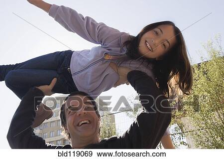 Stock Photo - Hispanic man lifting daughter over his head. Fotosearch