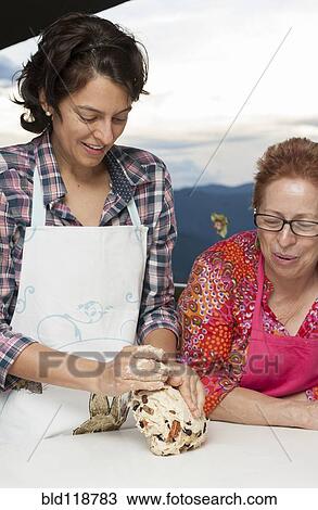 Stock Image - Hispanic mother and daughter baking together. Fotosearch