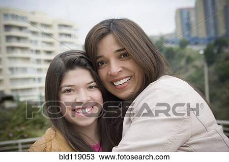 Stock Image - Hispanic mother and daughter smiling outdoors. Fotosearch