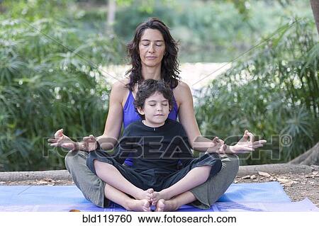 Stock Image - Hispanic mother and son practicing yoga. Fotosearch