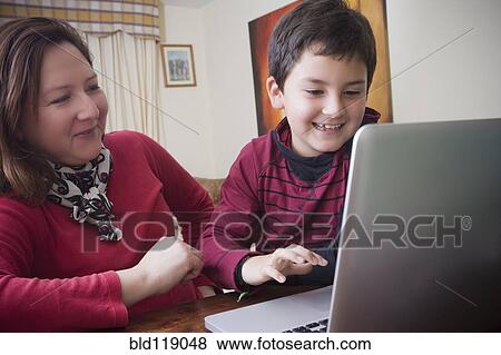 Stock Photo - Hispanic mother and son using laptop together. Fotosearch