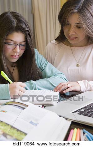 Picture - Hispanic mother helping daughter with homework. Fotosearch