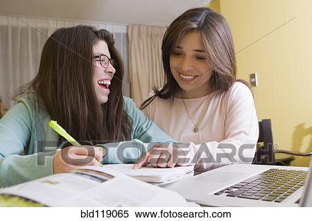 Stock Photography - Hispanic mother helping daughter with homework. Fotosearch