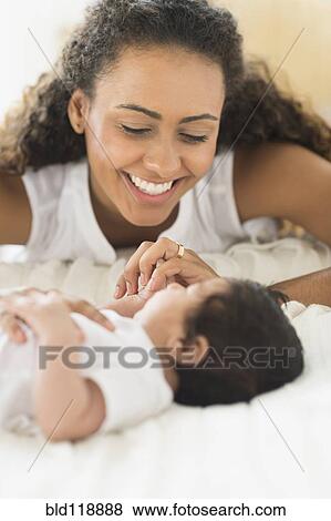 Stock Photo - Hispanic mother playing with infant son. Fotosearch