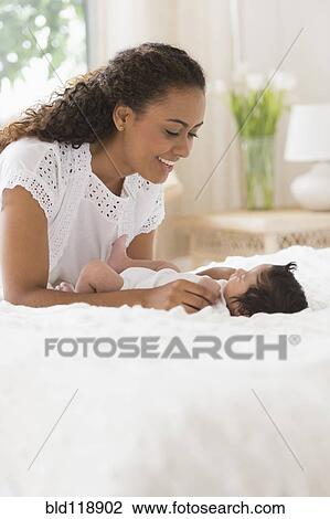 Stock Image - Hispanic mother playing with infant. Fotosearch