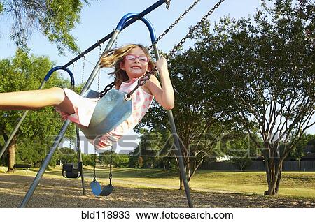 Stock Image - Hispanic playing on swings in park. Fotosearch