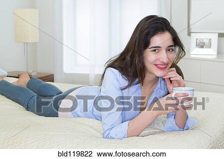 Hispanic woman enjoying cup of coffee on bed View Large Photo Image Stock Image - Hispanic woman enjoying cup of coffee on bed. Fotosearch