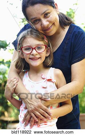 Stock Image - Hispanic woman hugging daughter outdoors. Fotosearch