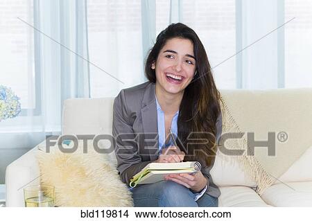 Hispanic woman taking notes on sofa View Large Photo Image Picture - Hispanic woman taking notes on sofa. Fotosearch