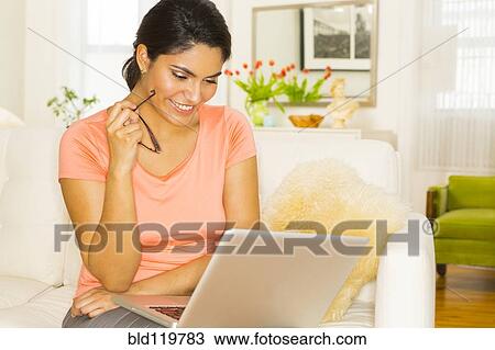 Hispanic woman using laptop on sofa View Large Photo Image Stock Image - Hispanic woman using laptop on sofa. Fotosearch