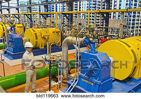 Stock Image - Hispanic worker checking machinery. Fotosearch
