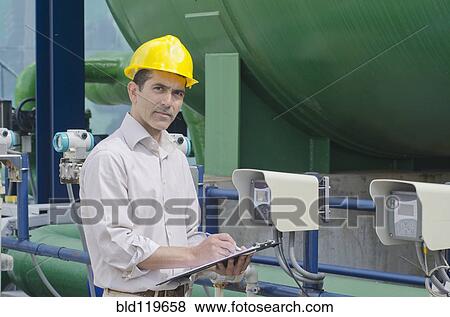 Stock Photo - Hispanic worker checking machinery. Fotosearch