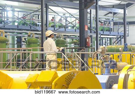 Stock Photo - Hispanic worker checking machinery. Fotosearch
