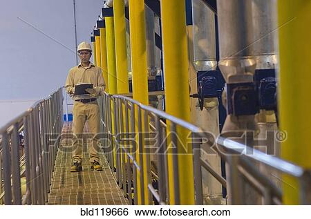 Stock Photograph - Hispanic worker checking machinery. Fotosearch