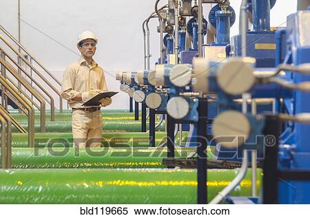 Stock Photography - Hispanic worker checking machinery. Fotosearch