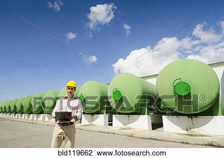 Stock Image - Hispanic worker checking tanks. Fotosearch