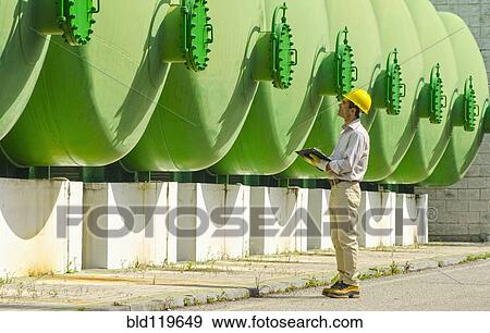 Stock Photo - Hispanic worker checking tanks. Fotosearch