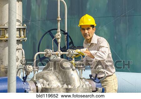 Stock Image - Hispanic worker checking valves. Fotosearch