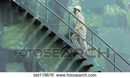 Stock Photograph - Hispanic worker climbing water tower. Fotosearch
