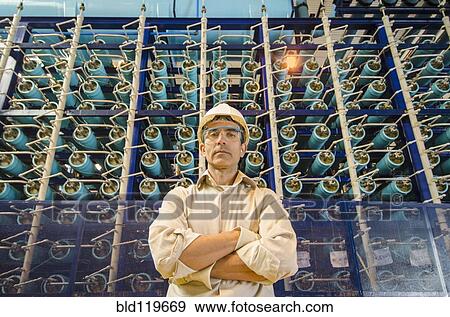 Stock Photo - Hispanic worker standing in factory. Fotosearch