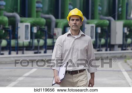 Stock Photograph - Hispanic worker wearing hard hat outdoors. Fotosearch