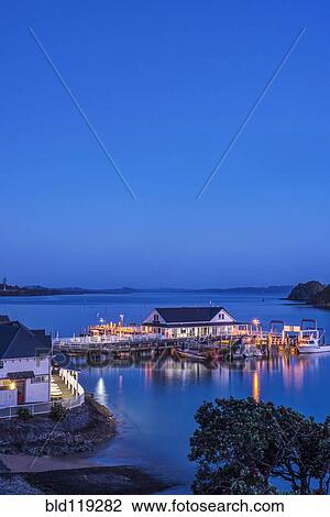 Stock Image - Illuminated building on water at dawn. Fotosearch
