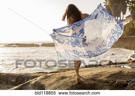 Stock Photography - Japanese woman holding sarong on beach. Fotosearch