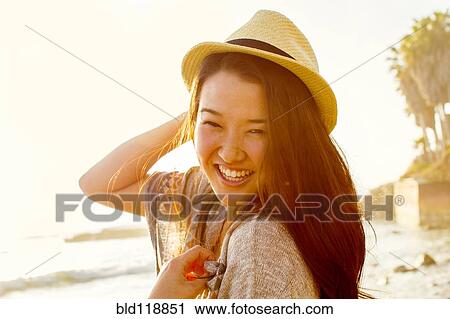 Stock Image - Japanese woman smiling on beach. Fotosearch