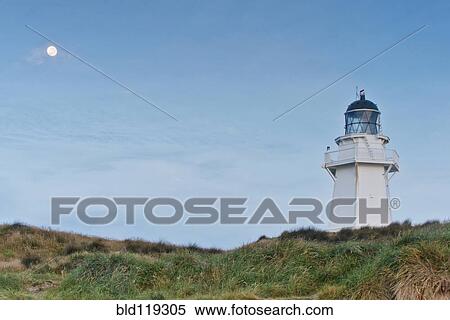 Stock Photography - Lighthouse under moon in blue sky. Fotosearch