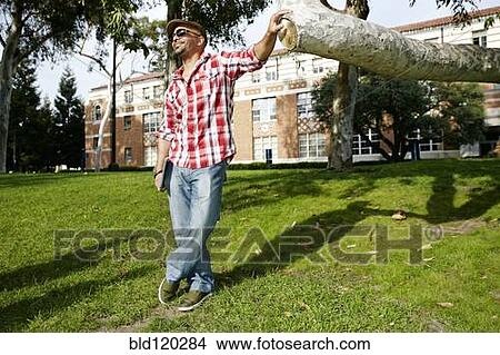Man leaning against tree branch in park View Large Photo Image Picture - Man leaning against tree branch in park. Fotosearch
