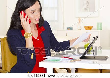 Stock Image - Mixed race businesswoman working at desk. Fotosearch
