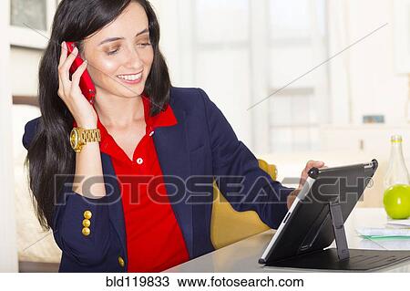 Stock Image - Mixed race businesswoman working at desk. Fotosearch