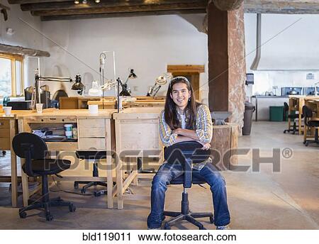 Stock Image - Mixed race man sitting in art studio. Fotosearch