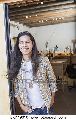 Stock Image - Mixed race man standing in doorway of art studio. Fotosearch