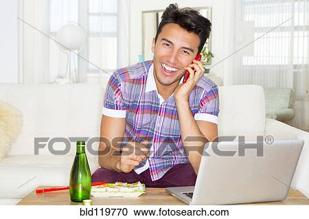 Stock Image - Mixed race teenager using laptop and cell phone. Fotosearch