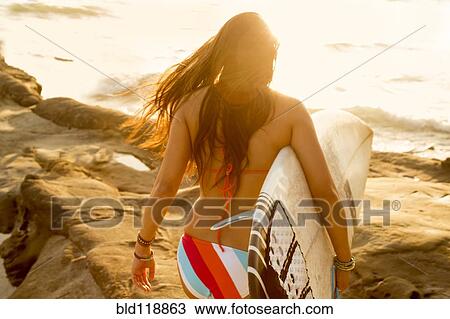 Mixed race woman carrying surfboard on beach View Large Photo Image Stock Image - Mixed race woman carrying surfboard on beach. Fotosearch