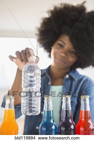 Picture - Mixed race woman choosing water over soda. Fotosearch