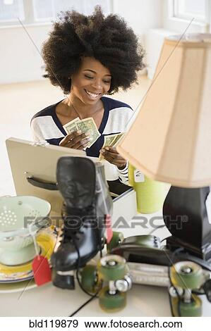 Mixed race woman counting money from yard sale View Large Photo Image Stock Photo - Mixed race woman counting money from yard sale. Fotosearch
