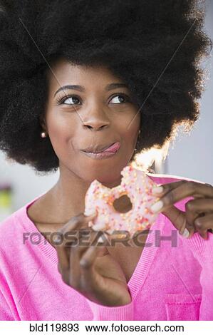 Mixed race woman eating donut View Large Photo Image Stock Image - Mixed race woman eating donut. Fotosearch