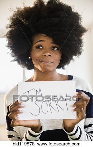 Stock Photo - Mixed race woman holding "I'm sorry" sign. Fotosearch