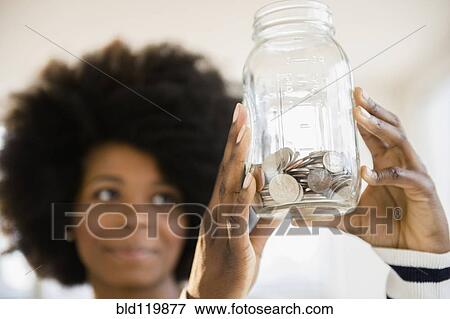 Mixed race woman holding jar of change View Large Photo Image Stock Photo - Mixed race woman holding jar of change. Fotosearch