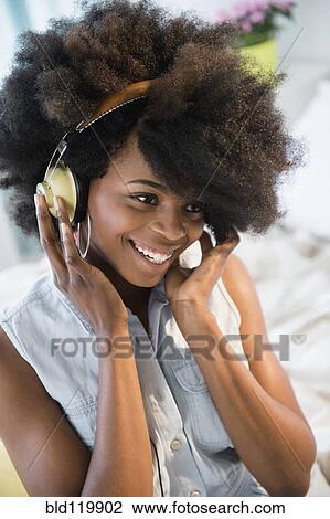 Stock Image - Mixed race woman listening to headphones. Fotosearch