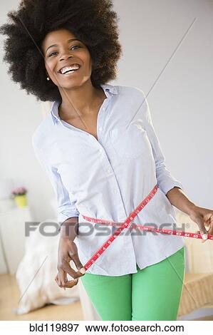 Mixed race woman measuring her waist View Large Photo Image Stock Photo - Mixed race woman measuring her waist. Fotosearch
