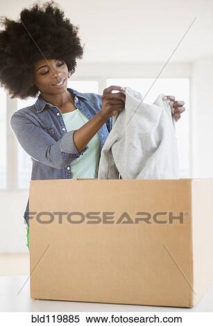 Mixed race woman placing sweater in cardboard box View Large Photo Image Stock Photography - Mixed race woman placing sweater in cardboard box. Fotosearch